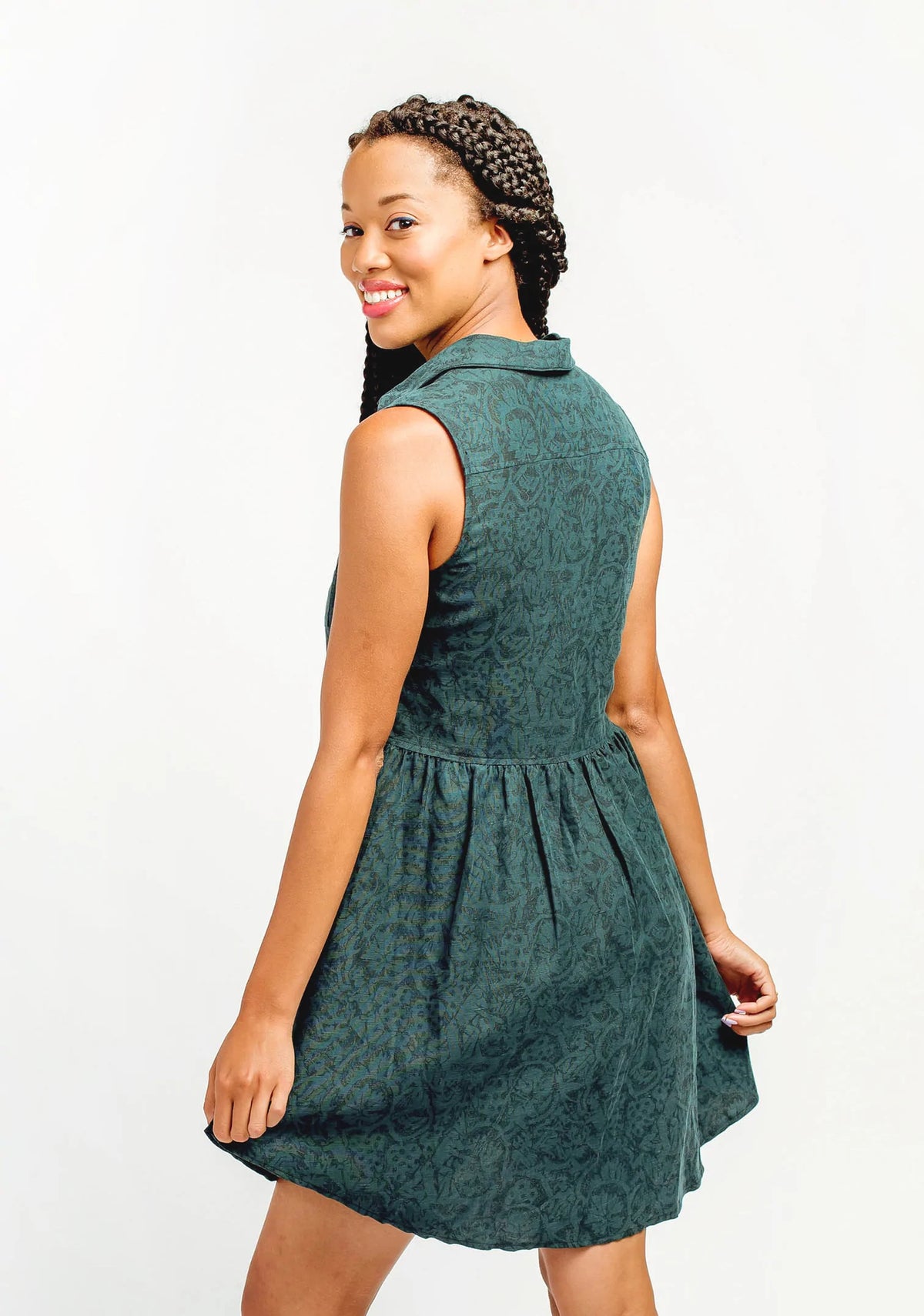 Model Lauren is wearing a size 8, view B Alder Shirtdress in a green patterned fabric. She is showing the back side of the shirtdress.