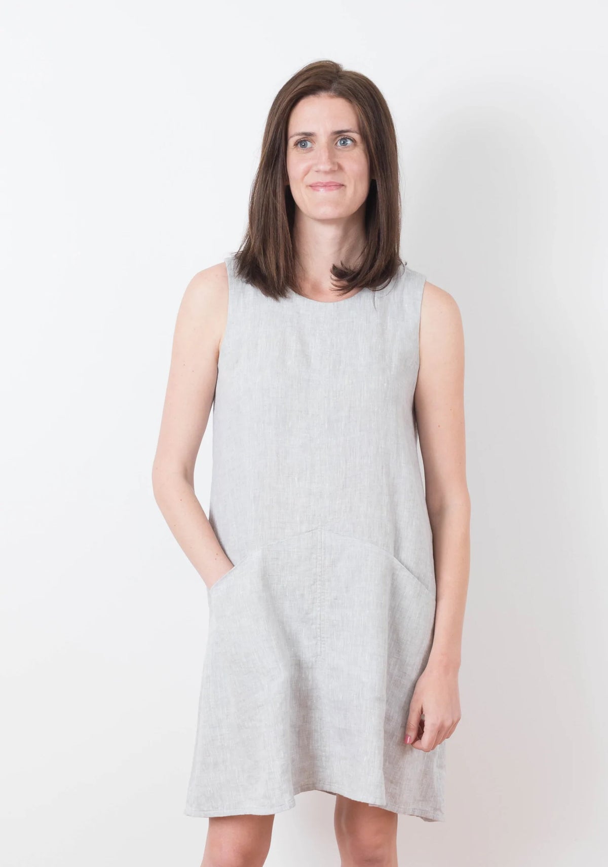 Model Kari is wearing a size 6 Farrow in a light colored linen fabric, front view sleeveless with pockets.